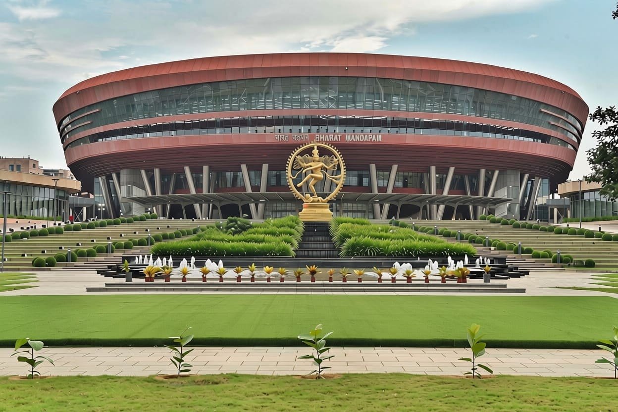 Bharat Mandapam at Pragati Maidan seen from the front — a low circular convention centre behind a landscaped forecourt with a golden Nataraja statue.